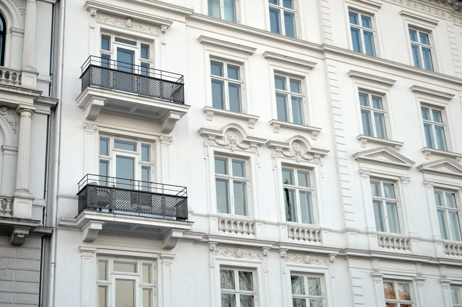 Fachada clásica blanca con balcones de forja y ventanas altas